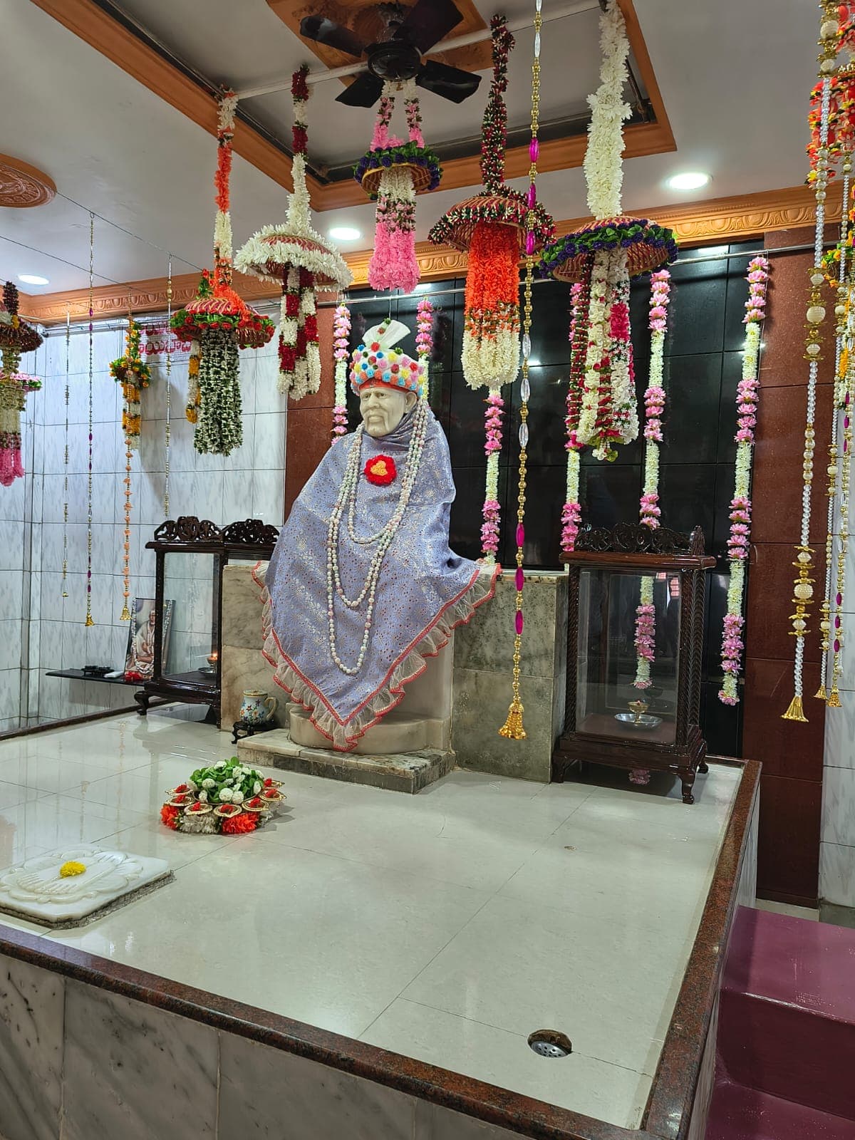 Close view of the murti dressed in a bright pink shawl with layered pearl garlands