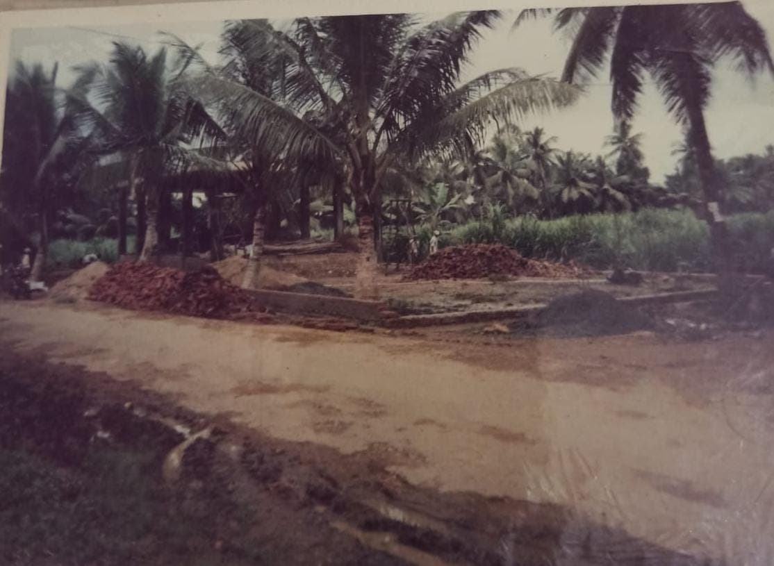Piles of bricks at the temple construction site, surrounded by coconut palms