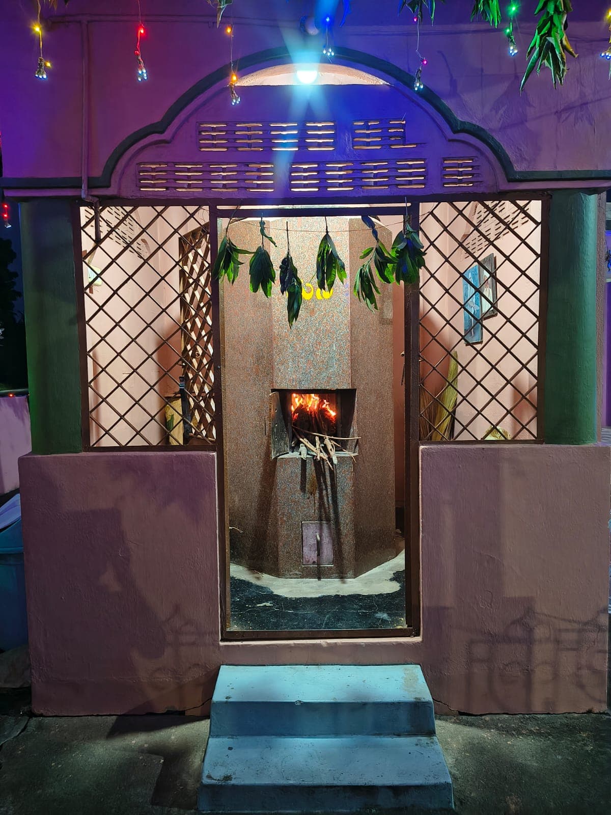 The Dhuni shrine's doorway at night, lit from within with the fire visible inside