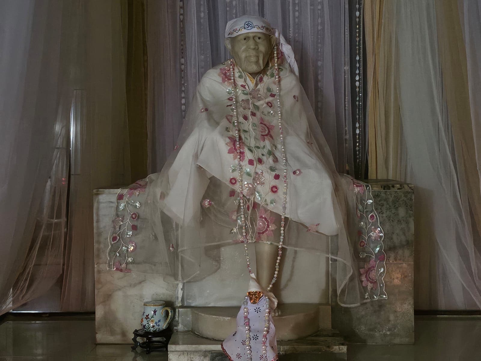 The main murti veiled in white and pink floral drapery, garlanded, present day